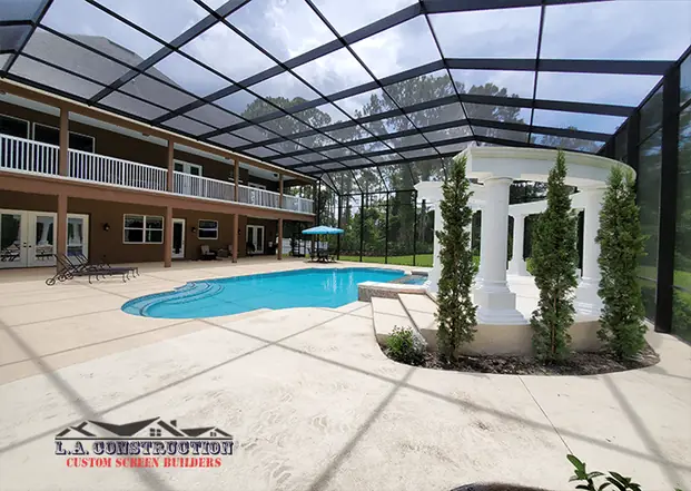 Two-story pool cage in DeBary, FL enclosing the pool, white column pergola and the home's upper balcony