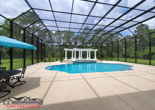 Wide pool screen enclosure in DeBary, FL over a pool, spa with white columns, and patio furniture