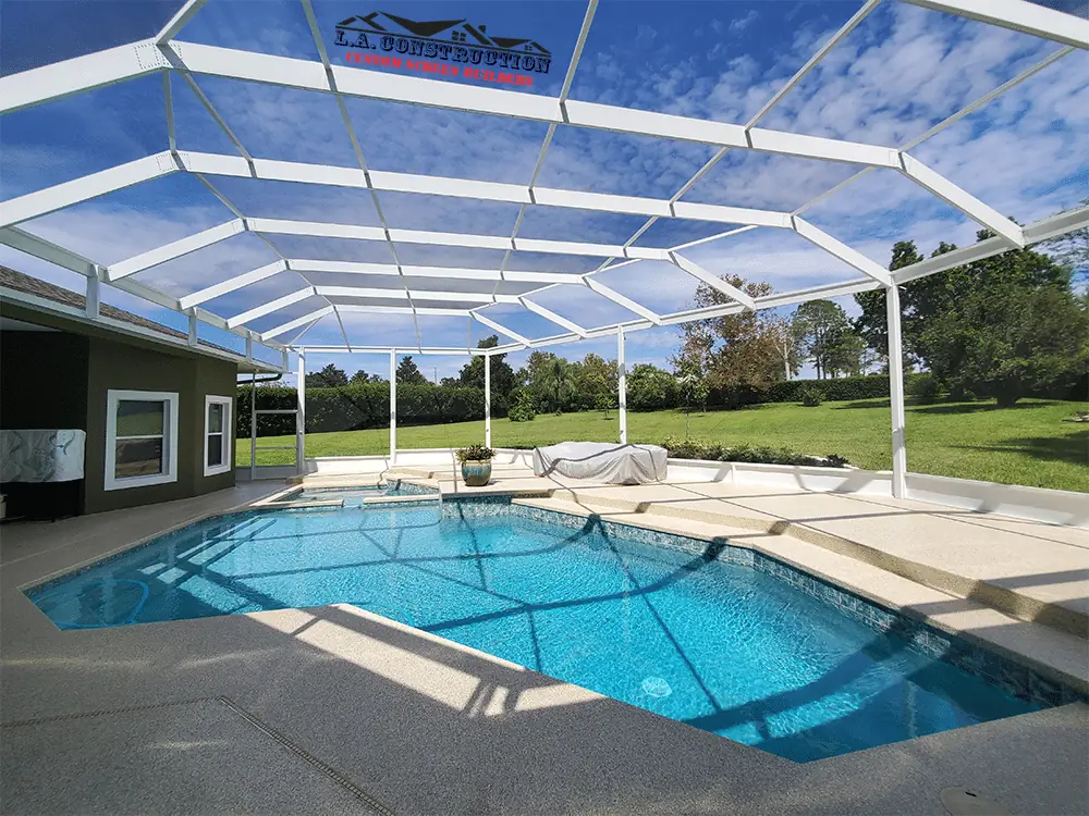 White mansard-style pool cage over a pool and deck, open to a wide lawn