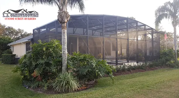 Dome-style pool cage behind a home in Ormond Beach, FL, with palm trees and landscaping in front