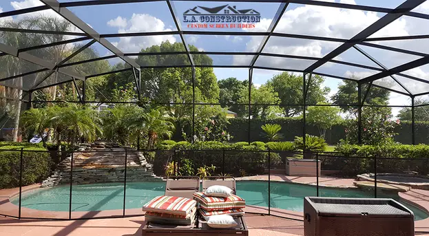 Dome pool cage in Windermere over a pool with a stone waterfall, lounge chairs and tropical plants